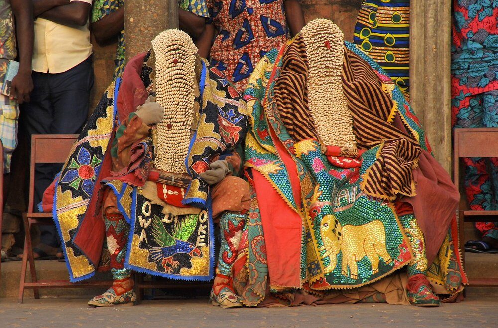 Two Egungun masquerades are sitting next to each other.
